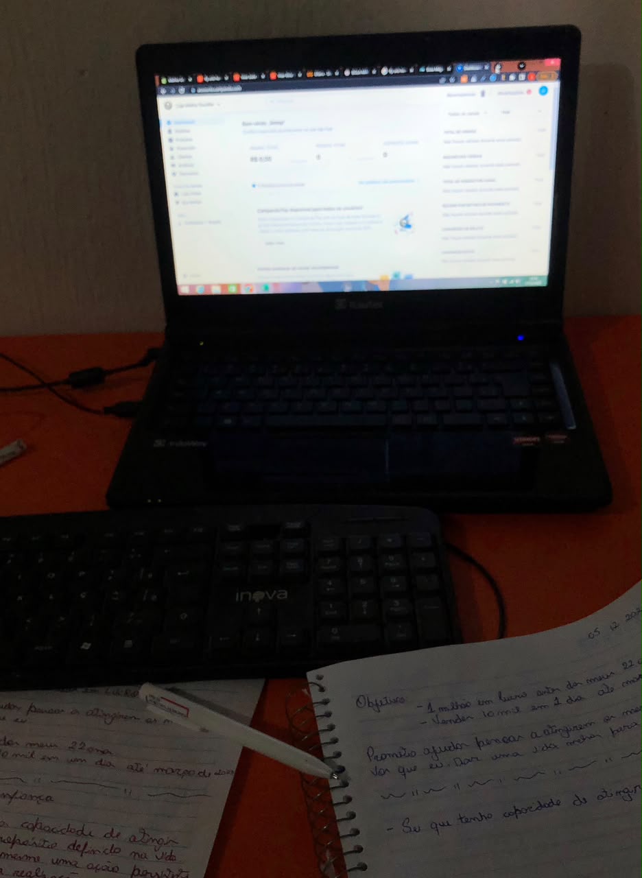 Notebook sobre uma mesa, com cadernos de anotações em primeiro plano
