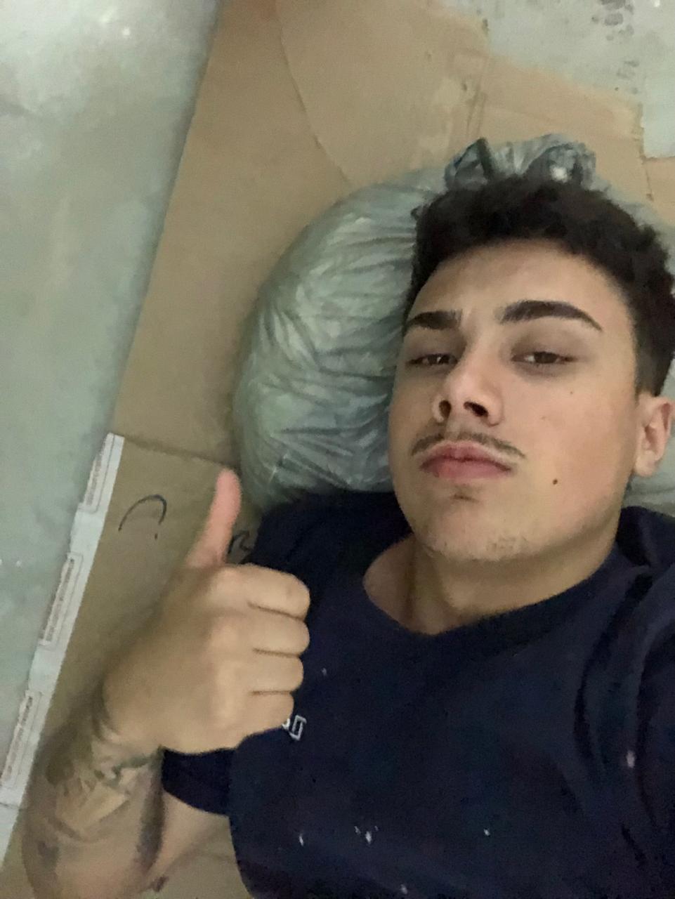 Dimi deitado sobre papelões durante uma fase de trabalho sem estrutura pronta